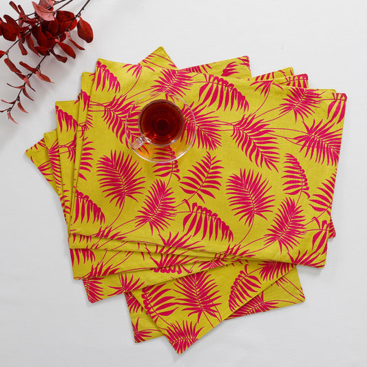 Sunny and cheerful cotton placemat featuring a vibrant leaf print in shades of yellow and pink, perfect for adding a touch of nature's warmth to your dining table.