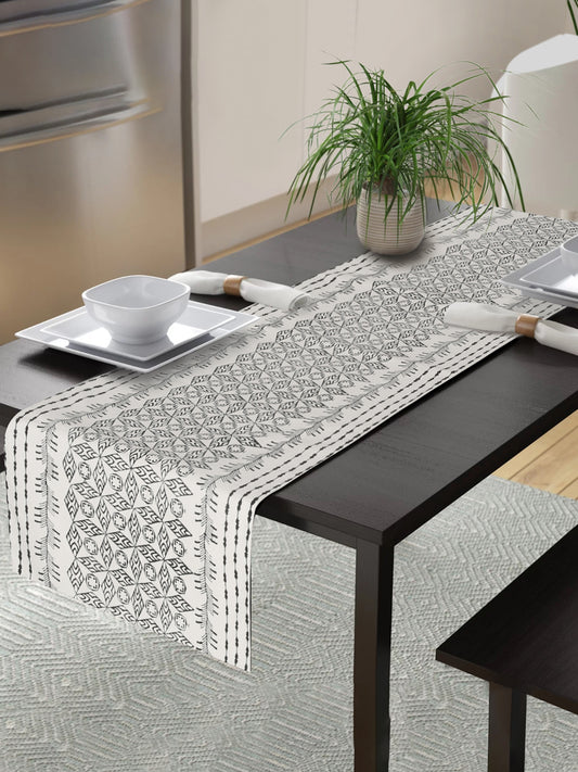 A black and white table runner with a diamond pattern adds a touch of rustic elegance to any dining space.