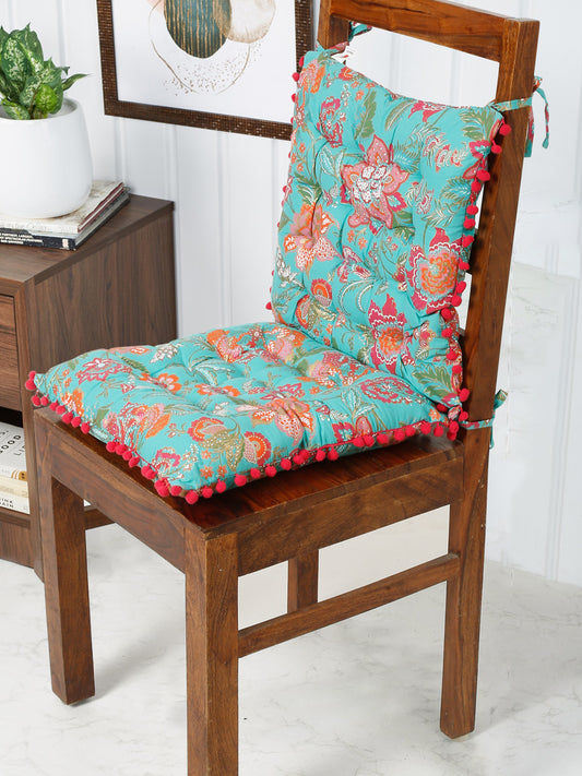 Cheerful chair pad with a vibrant blue floral design and playful red pom pom trim, adding a touch of whimsy to any chair.